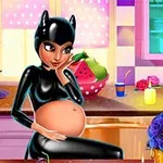 En gravid kvinna i svart dräkt med kattöron sitter vid ett bord i ett färgglatt kök med levande ljus och blommor