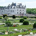 Ett storslaget slott i bakgrunden med välskötta trädgårdar och blomsterarrangemang i förgrunden