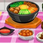 En dukning med olika asiatiska maträtter, inklusive en skål med grönsaker och svamp, kimchi, och en kopp te på en rosa-rutig duk