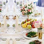 Ett elegant dukat bord med vit duk, dekorerat med blommor, fruktfat och vikta servetter