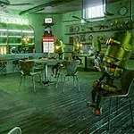 En futuristisk bar med gröna neonljus där robotar sitter vid borden i en rustik miljö