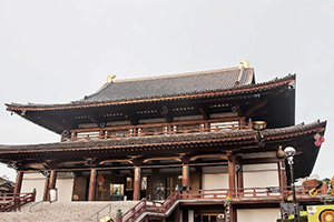 En traditionell japansk tempelbyggnad med ett stort tak och träsniderier mot en ljus himmel