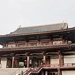 En traditionell japansk tempelbyggnad med ett stort tak och träsniderier mot en ljus himmel