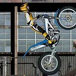 Motorcyklist i gul och svart dräkt gör ett bakhjulstrick inomhus