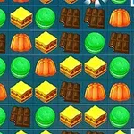 Flera rader av färgglada sötsaker, inklusive choklad, gelégodis och bakverk, arrangerade på ett spelbräde