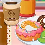 Kaffekopp med två dekorerade donuts och skivad kiwi på ett fat