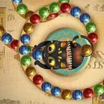 En svart kattstaty med färgglada kulor i en spiral på en bakgrund med egyptiska hieroglyfer